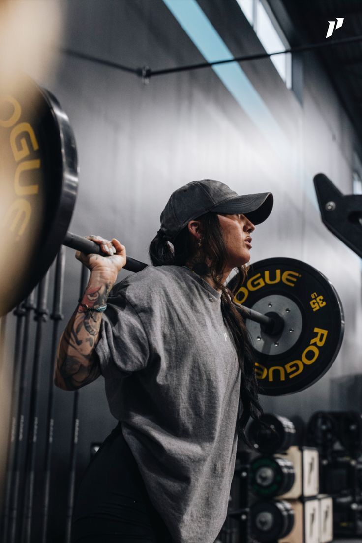 A lifter braced under a loaded barbell in a moody industrial gym